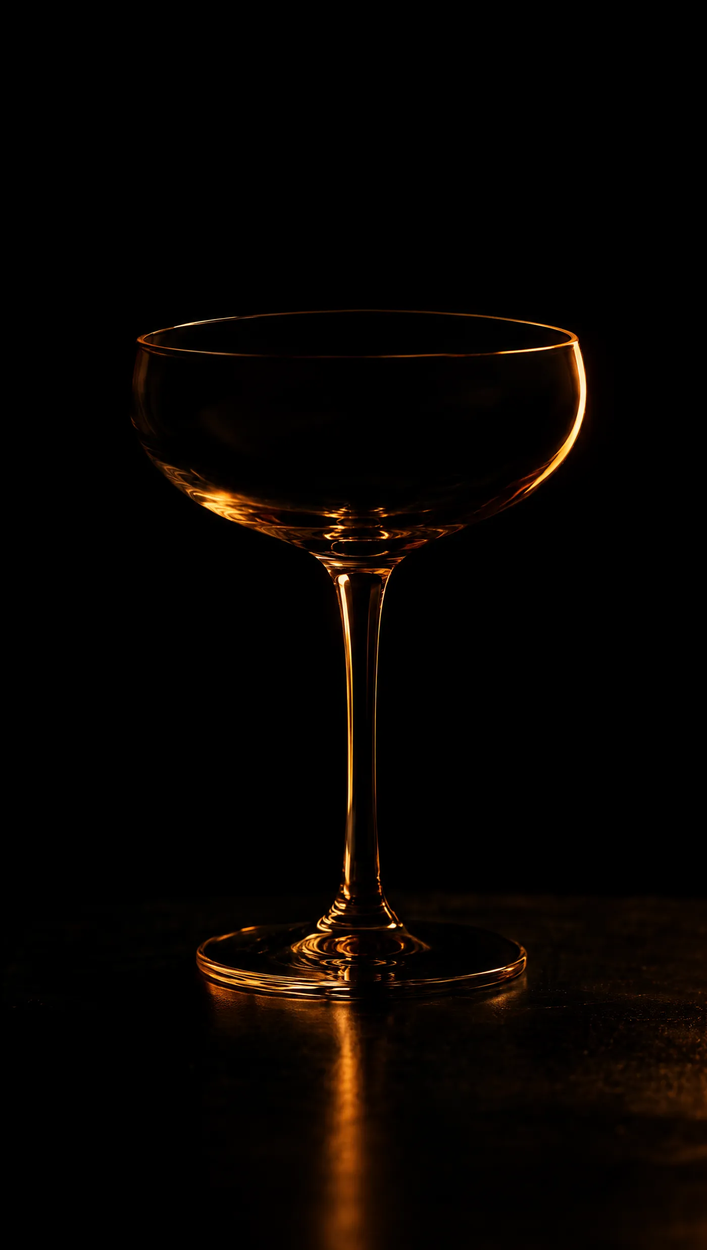 A coupe glass picked out by a single warm rim light